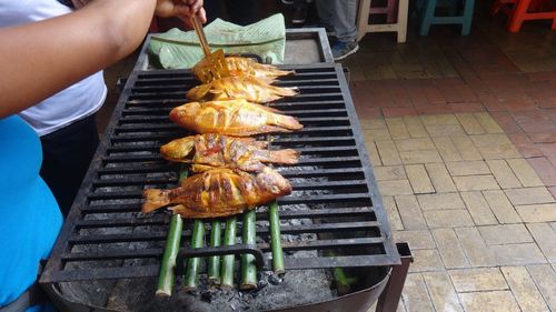 Midsection of people cooking fish on barbecue
