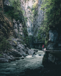 Man standing on cliff by river