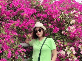 Beautiful woman with pink flower against plants