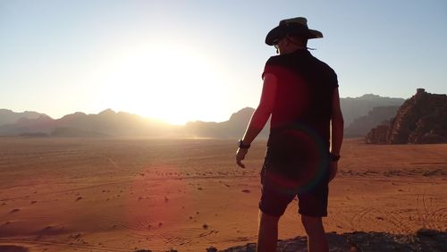 Man standing at desert against sky during sunset