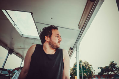 Low angle view of young man standing against sky being anxious, anxiety