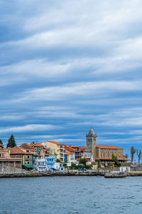 Buildings by river against sky