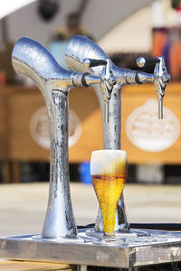 Close-up of glass under beer tap 