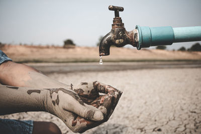 Close-up of hand with faucet in water
