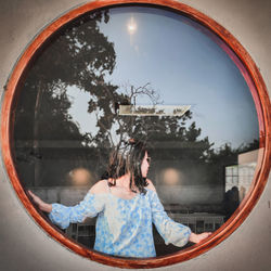 Portrait of young woman looking through window