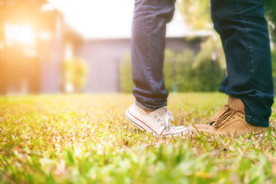 Low section of couple standing on field