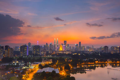 Distant view of petronas towers against sky during sunset in city