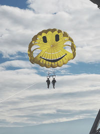 Low angle view of people paragliding against sky