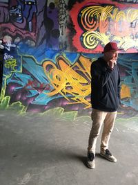 Full length of man standing against graffiti wall