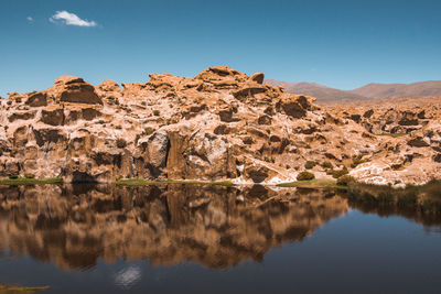 Scenic view of rocky mountains reflecting on lake against blue sky