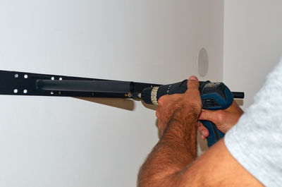 Close-up of man holding hand against wall