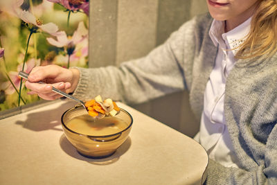 Midsection of woman holding while sitting on table