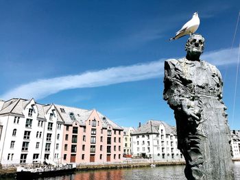 Statue by building in city against sky