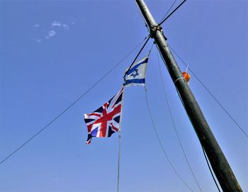 Low angle view of flags against clear blue sky