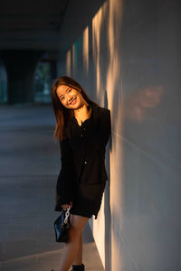 Portrait of young woman standing against wall
