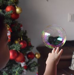 Close-up of boy touching bubble at home during christmas