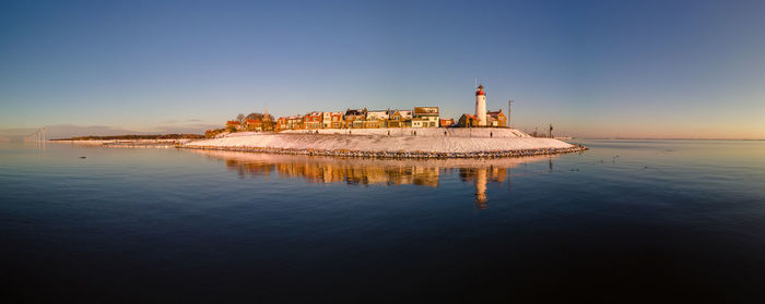 Reflection of building in sea against clear sky