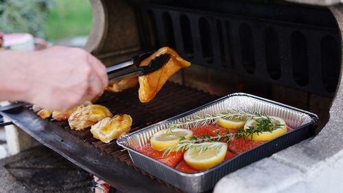 Midsection of person preparing food on barbecue grill