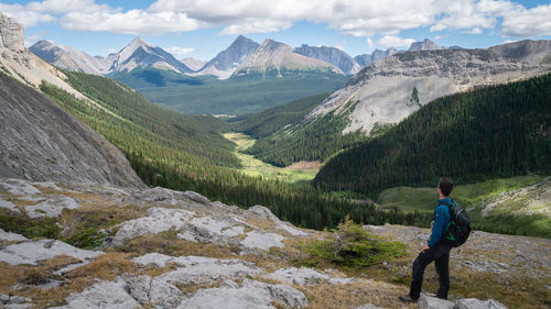 Rear view of man walking on mountain against sky