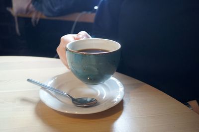 Close-up of hand holding coffee cup on table