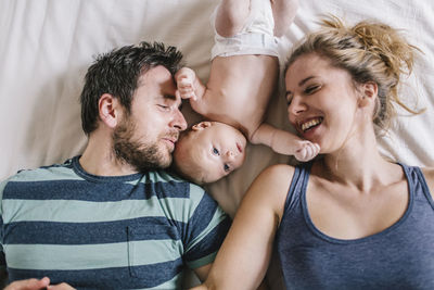 Mother and father with baby boy lying on bed