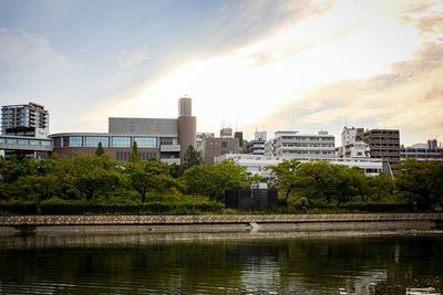 Buildings by river against sky in city