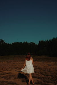 Woman standing on field against clear sky