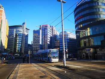 View of city street and buildings against blue sky