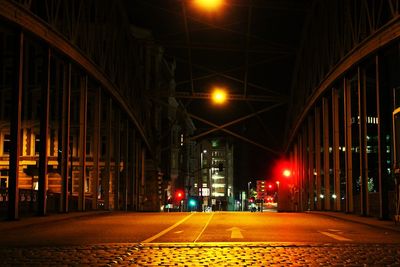 Illuminated street amidst buildings in city at night