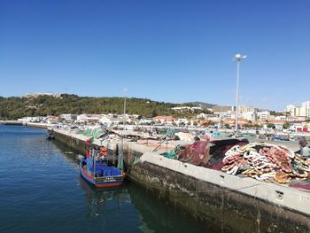 Boats moored at harbor against clear blue sky