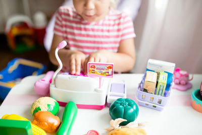 Little girl playing grocery store in on table with cash register