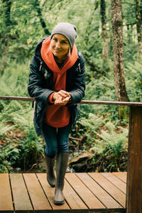 Portrait of a cheerful woman hiker resting leaning on the railing of a wooden bridge