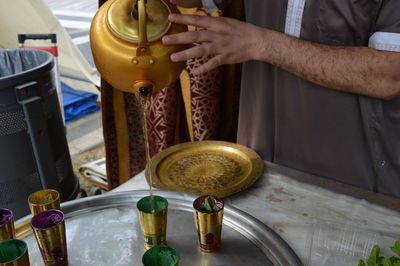 Midsection of man pouring tea in glass