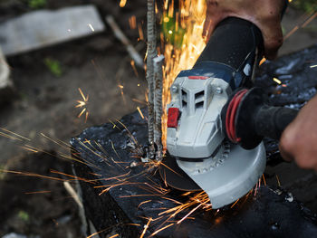 Worker cuts off excess reinforcement in the foundation using an angle grinder, metal sparks fly