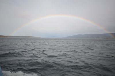 Scenic view of rainbow over sea against sky