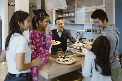 Happy family having pancake near kitchen counter at home