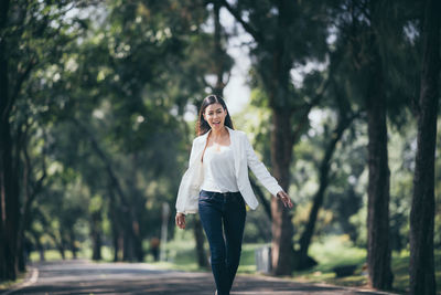 Full length of woman standing against trees