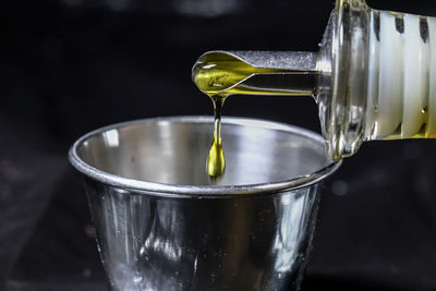 Close-up of glass pouring water in container