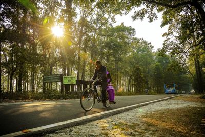 Man riding bicycle on road against trees