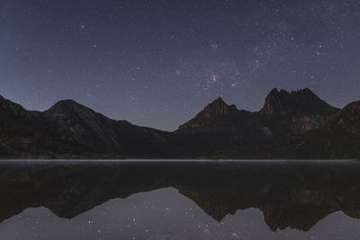 Scenic view of calm lake and mountains against sky at night