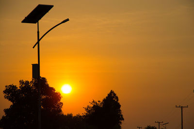 Silhouette street light against orange sky