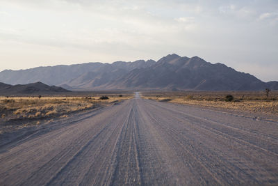 Road by desert against sky