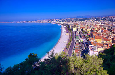 High angle view of townscape by sea against blue sky