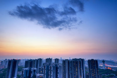 Modern buildings against sky during sunset