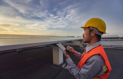 Engineers use a tablet to work on roof inspection and maintenance in a solar power plant, .