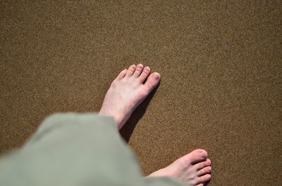 Low section of woman relaxing on sand at beach