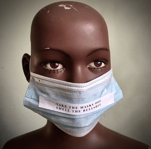 Portrait of young woman covering face against wall