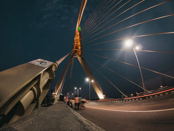 Illuminated ferris wheel on road against sky at night