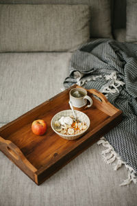 High angle view of breakfast on the couch at home, healthy eating, porridge, apple and tea.