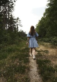 Rear view of woman walking on field